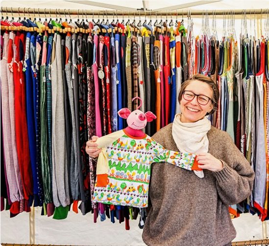 anna pollack mit einem T-Shirt auf einem Kleiderbügel mit Schweinchenkopf vor einem Ständer mit Piratenhosen
