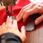 anna * pollack, An der Nähmaschine, roter Knisterfisch, gehalten von zwei Händen, anna pollack an der Arbeit, Mittleres Close Up